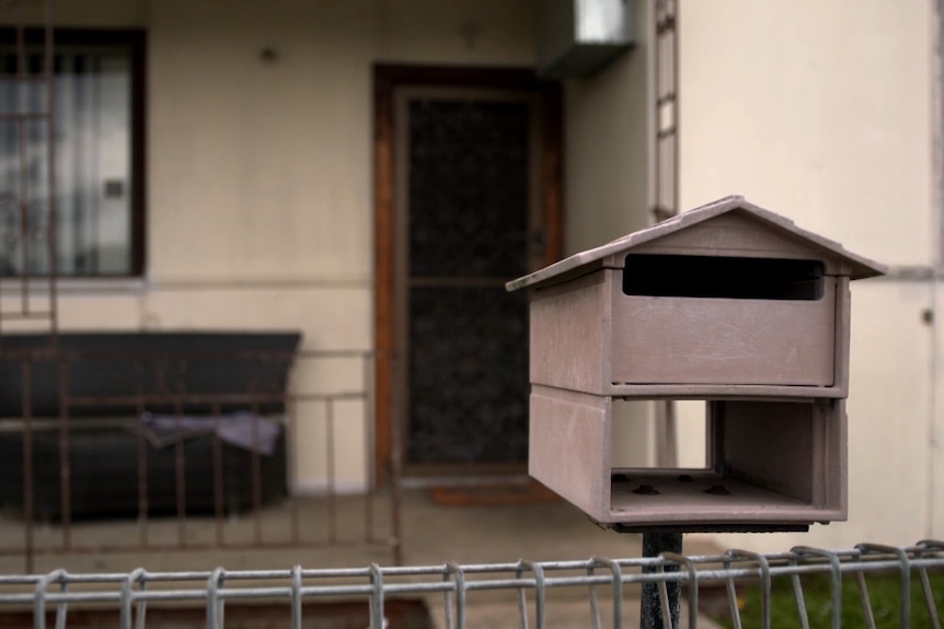 A letterbox behind the fence of a house.