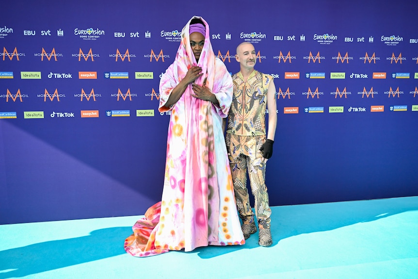 Zaachariaha Fielding wearing a pale pink patterned cloak and Michael Ross in a yellow-patterned suit