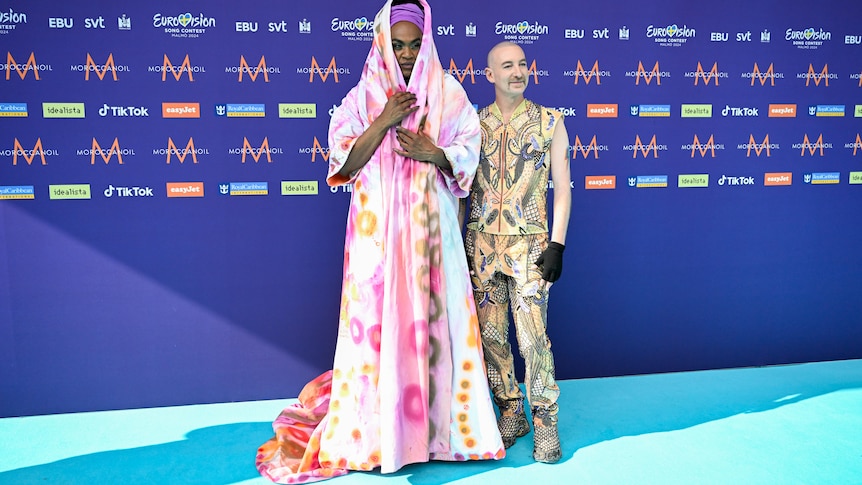 Zaachariaha Fielding wearing a pale pink patterned cloak and Michael Ross in a yellow-patterned suit