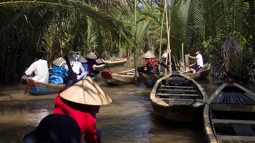 Tourists canoe down a tributary of the Mekong River.