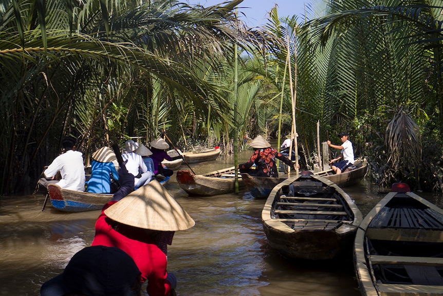 Tourists canoe down a tributary of the Mekong River.