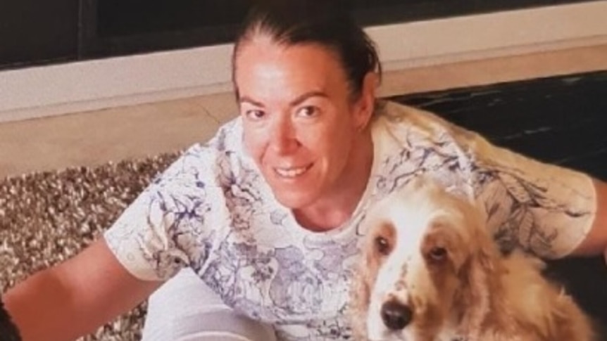 a woman sitting on the floor hugging a dog