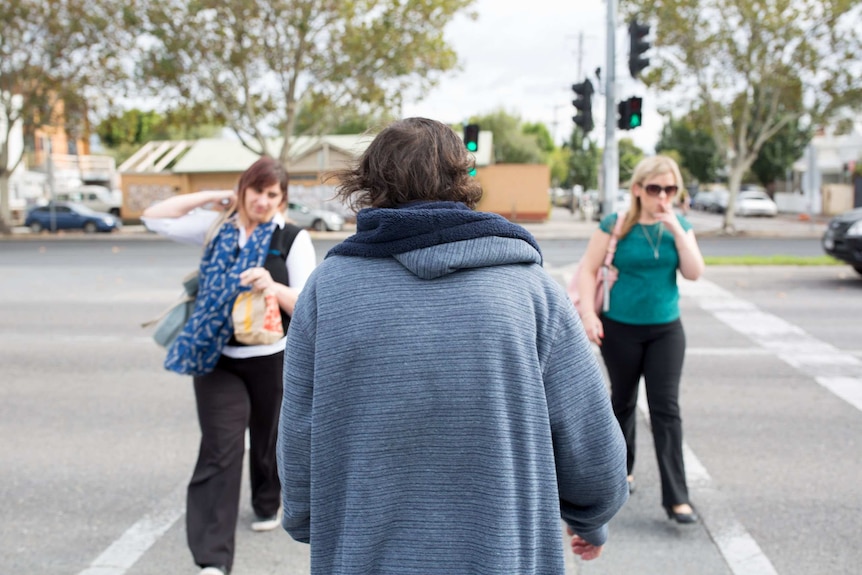 TJ Carpenter at a pedestrian crossing as two women pass him.
