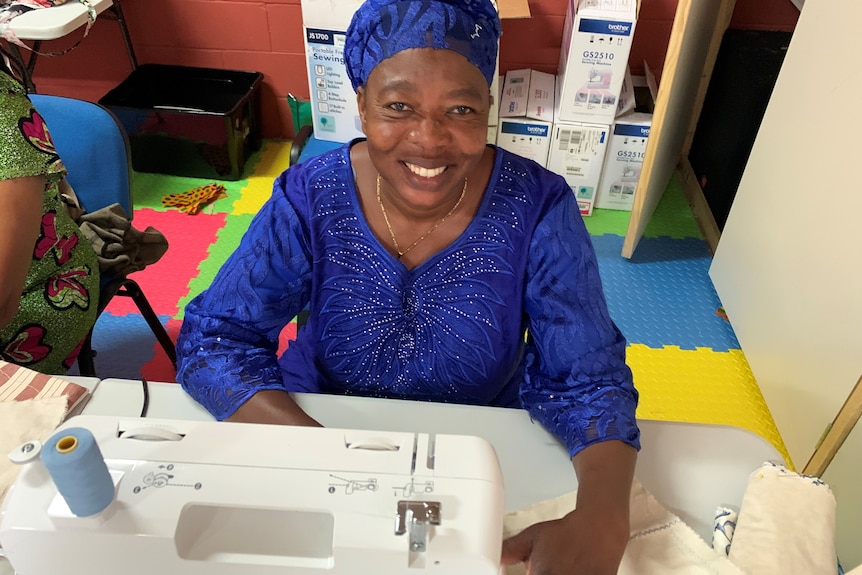 Congolese refugee Beatrice Neema smiles seated behind a sewing machine