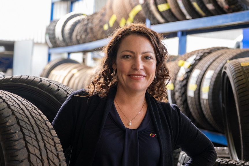 A woman smiling at the camera with racks of tyres in the background