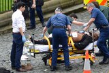 The London terrorist attacker is treated by emergency services while police look on in London on March 22, 2017