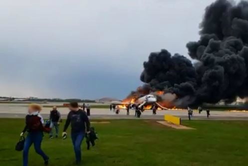 Smoke billows from burning plane with people running away from the wreck.