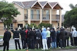 Relatives and residents stand in front of a house where Macchour Chaouk was shot dead