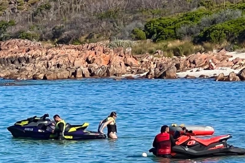 Two jet skis and users in the water, it's at quite a distance. 