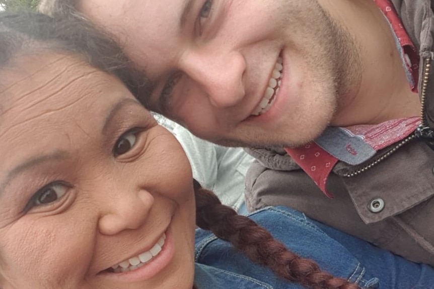 A brown-haired woman in a denim jacket smiles with a man in a brown jacket