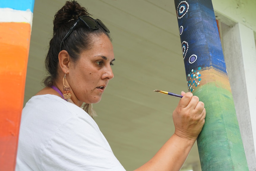 A woman painting totem poles.