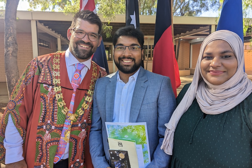 Mayor Matt Paterson stands with Seeni and Shameina in front of national flags.