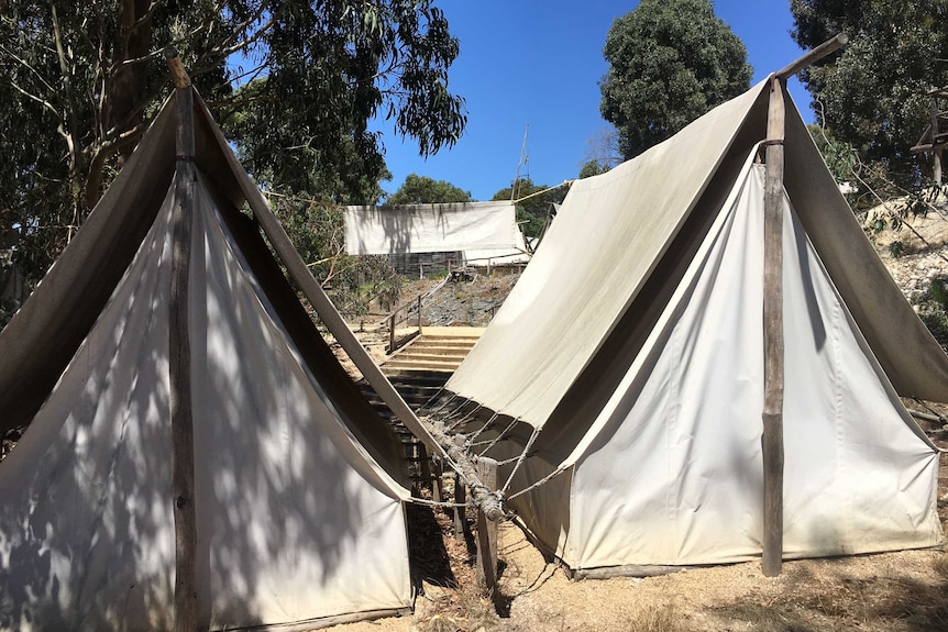 Canvas tents in the foreground at Ballarat's Sovereign Hill with trees and blue skies in the background.