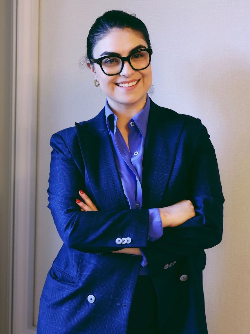 A portrait of a woman in glasses and a blue suit jacket. 