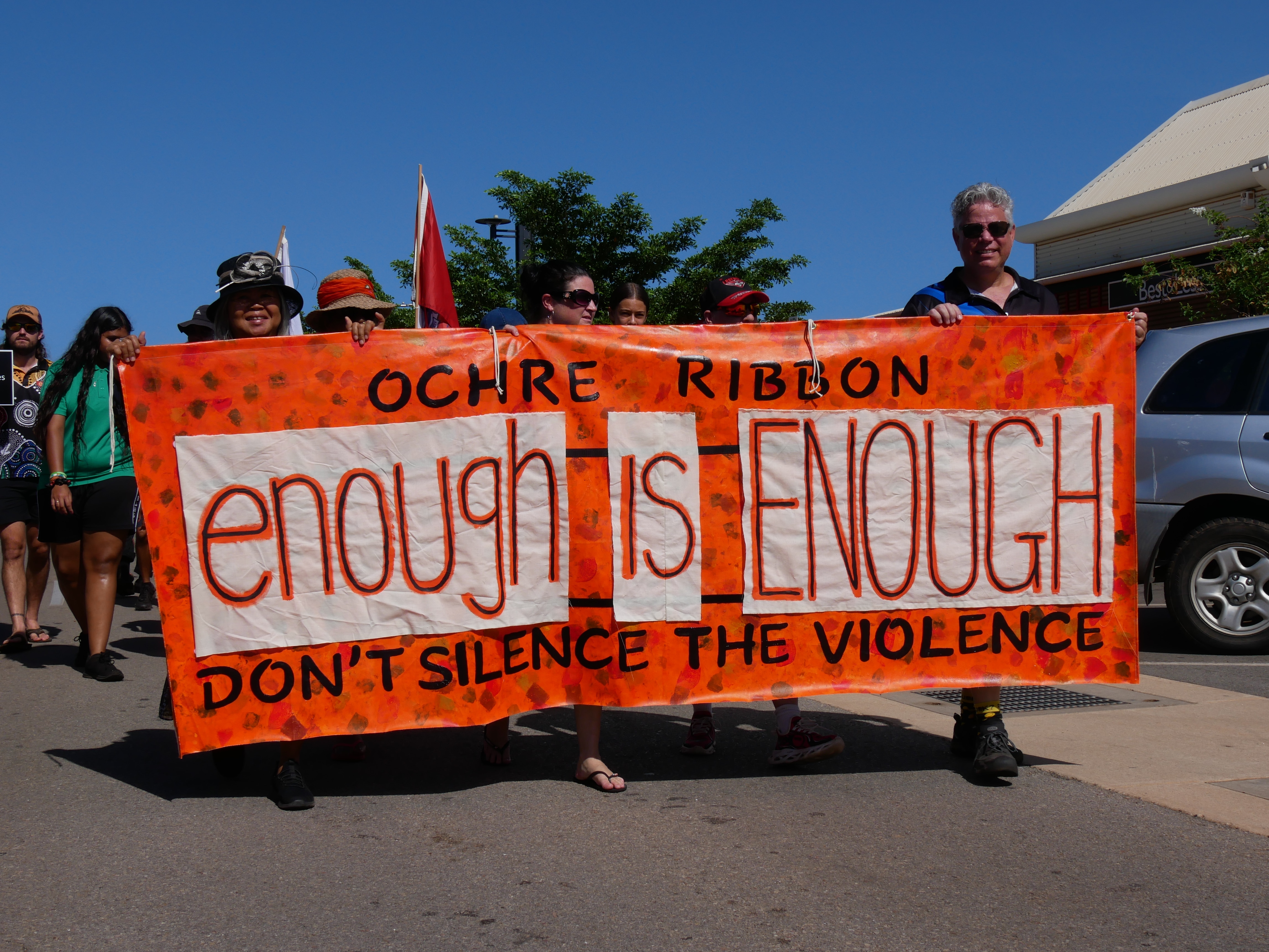 People walk on the street with an orange banner
