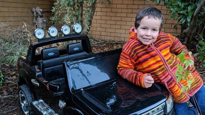 Phoenix Mapham leans on the bonnet of a small Ford Ranger.