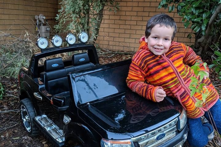 Phoenix Mapham leans on the bonnet of a small Ford Ranger.