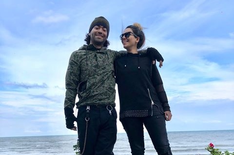 A photo of Mehdi and Mina with a beach in the background.