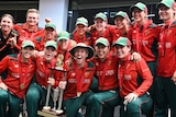 Players crowd together to pose with the trophy. 