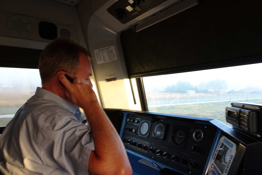 A man sits in the driver's compartment of a train.