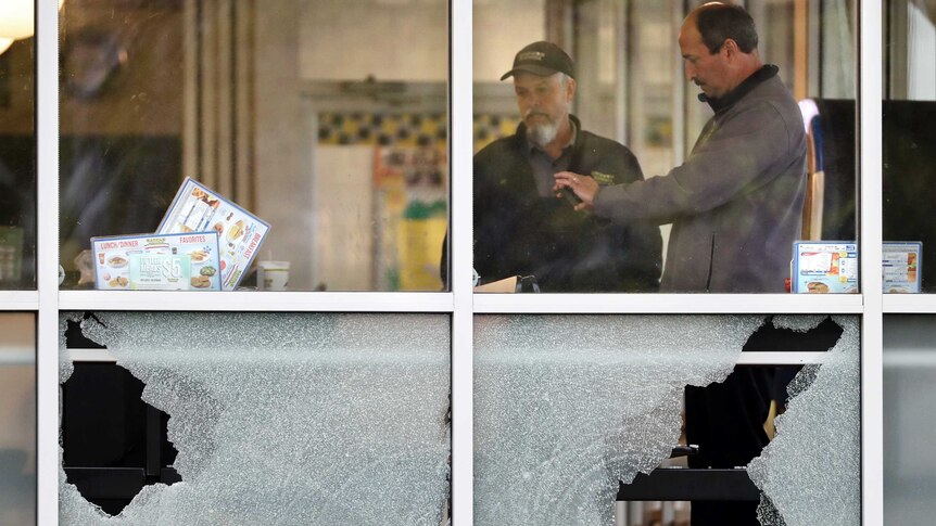 People standing inside the Waffle House restaurant, near broken windows.