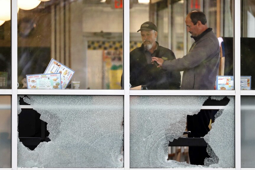 People standing inside the Waffle House restaurant, near broken windows.