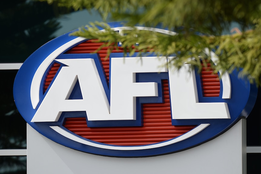 Логотип AFL на боковой стороне здания, частично закрытый веткой дерева.