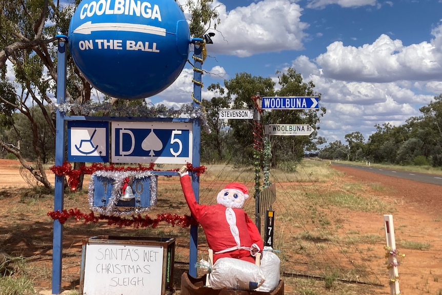 A Santa sits in a boat near a big blue ball sign saying 'Coolbinga on the ball'.