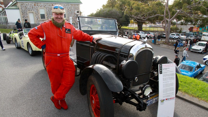 A motoring enthusiast stands beside his vintage car