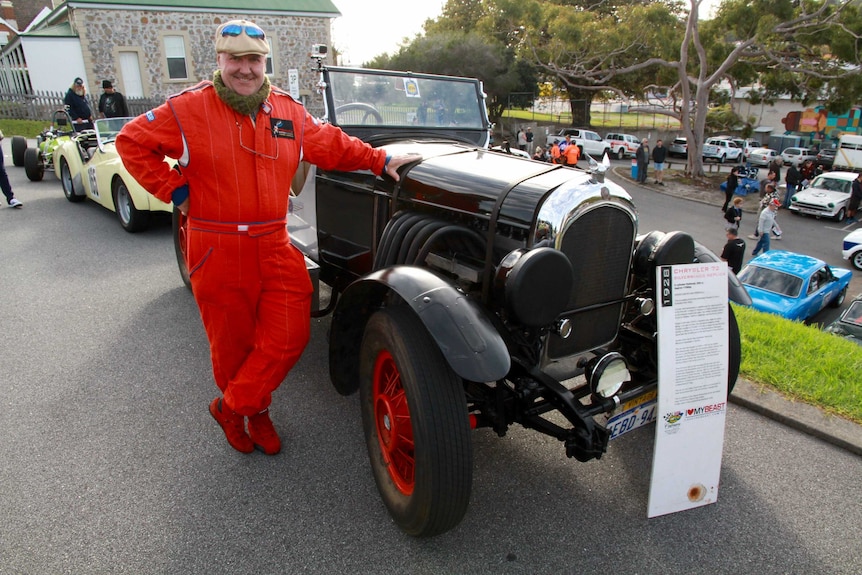 A motoring enthusiast stands beside his vintage car