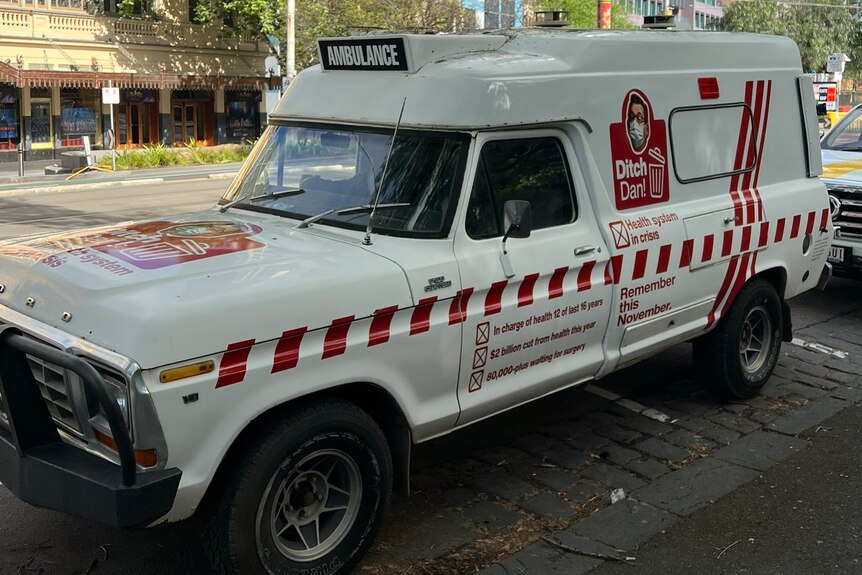 An old ambulance coverted into a Liberal Party campaign vehicle, plastered with slogans like 'Ditch Dan'.