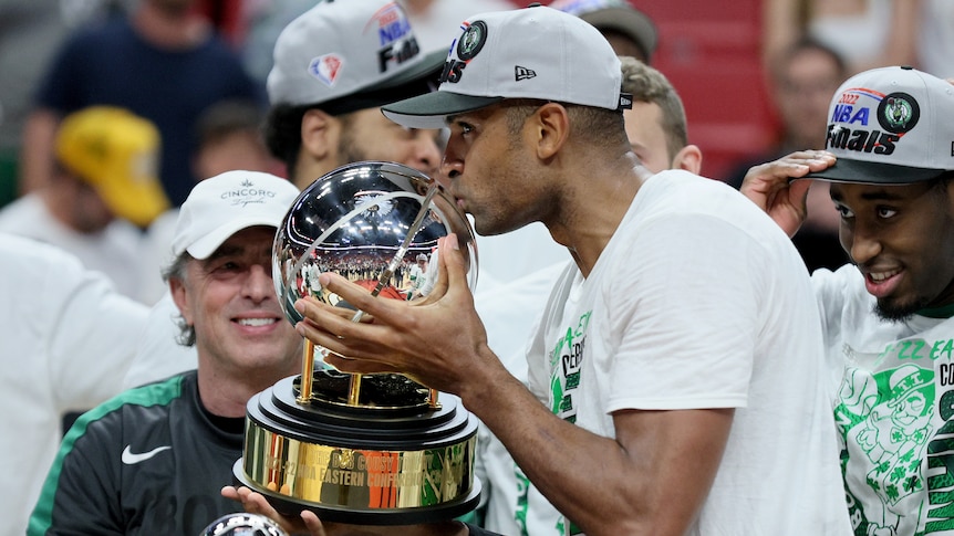 Al Horford kisses a large, basketball-shaped trophy