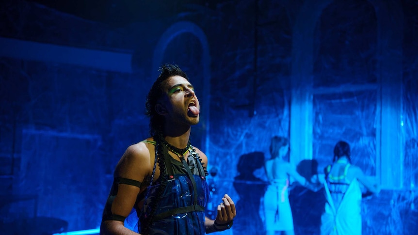 A gender non-conforming person sticking their tongue out during a theatre performance.