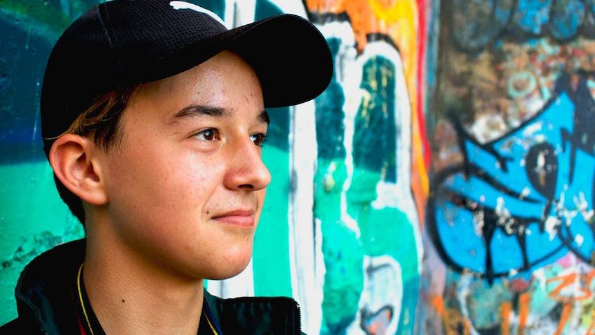 Teenager Alex Gatis wearing a black cap standing in front of a wall