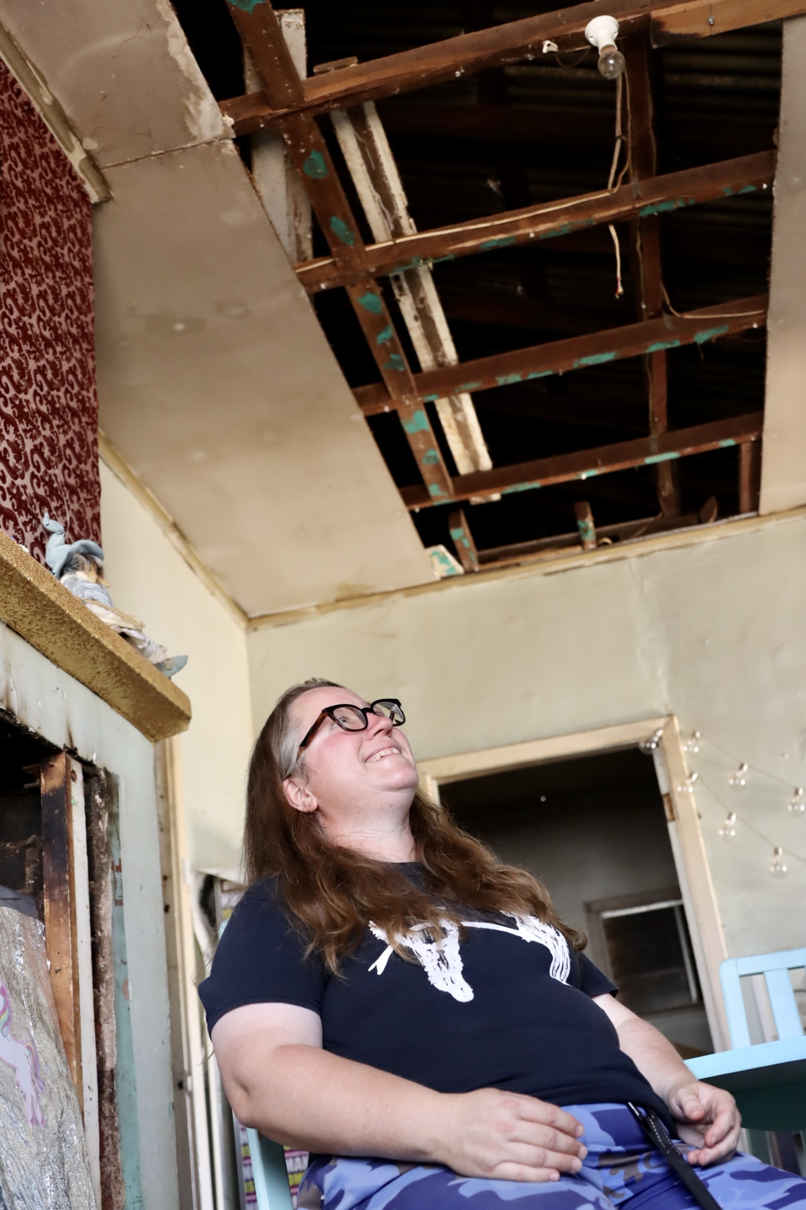 woman with glasses looking up at missing ceiling 