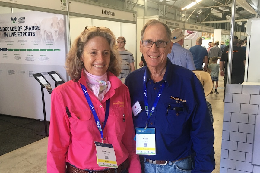 A man and woman stand together. There are in working shirts.