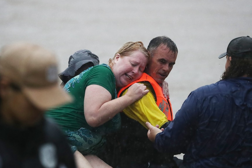 A woman clings to a man's back, while being surrounded by water.