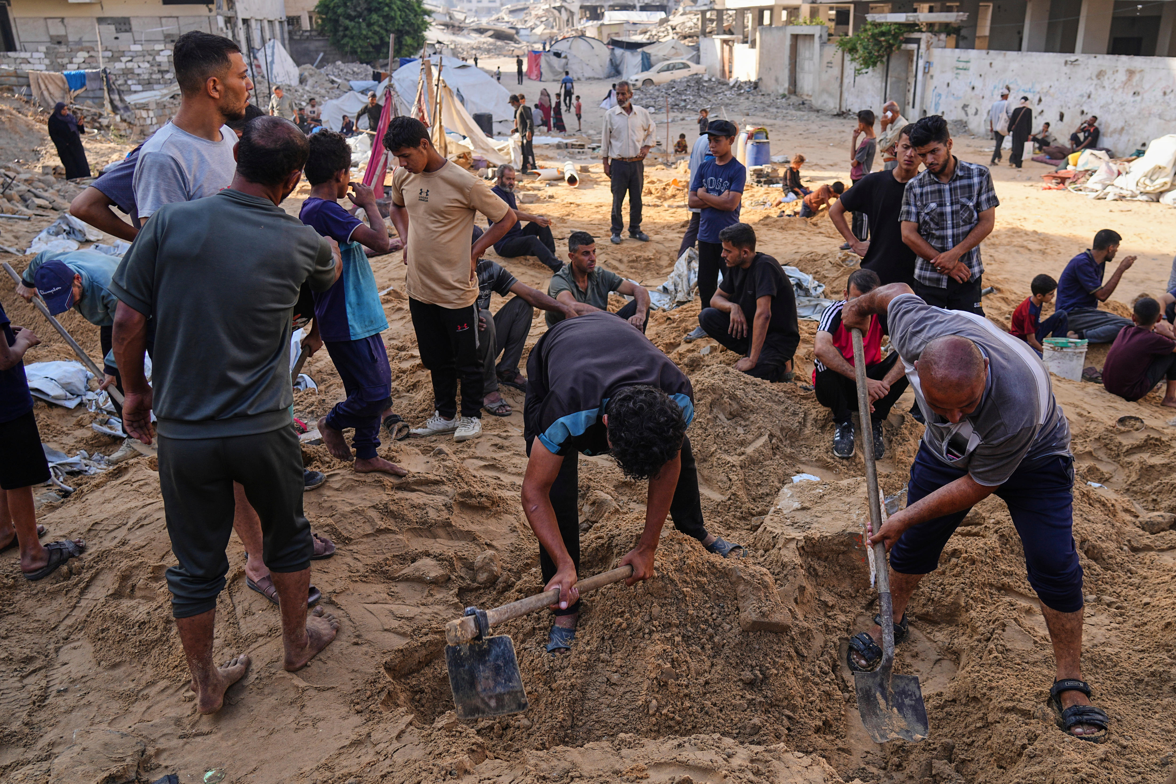 A group of people digging around in the in the sand. 