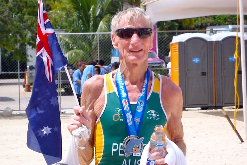 Triathlete Keith Pearce holding an Australian flag and wearing a medal.
