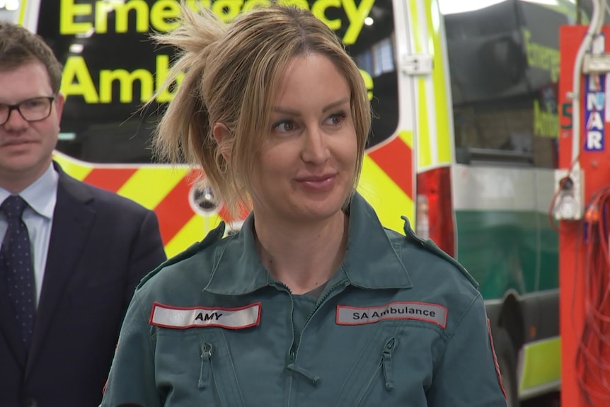 A woman in a paramedic uniform, an ambulance in the background