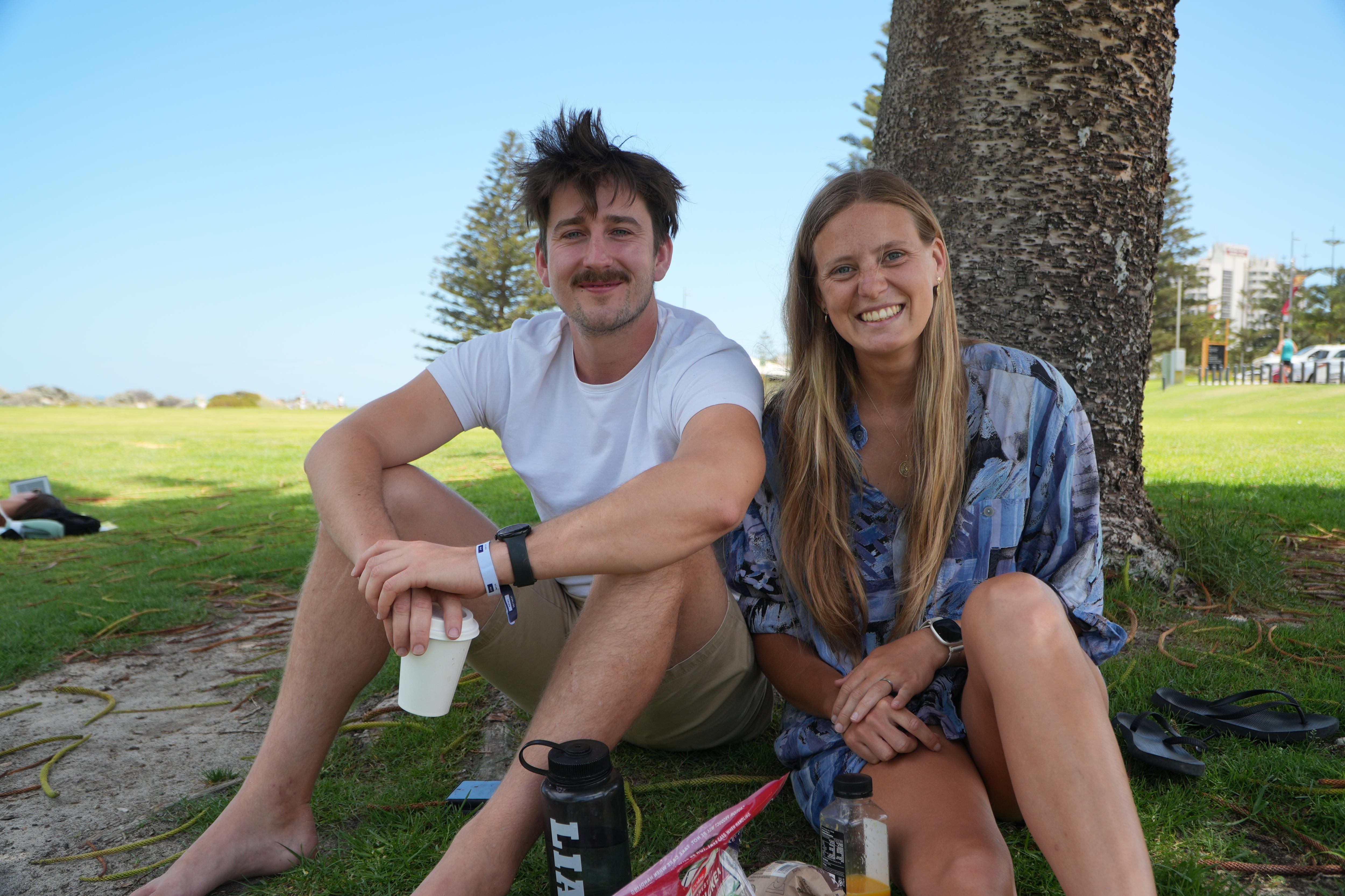 A young couple relax on a verdant hill.