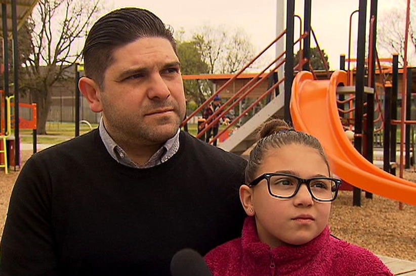 Ross Sicilian sitting in a playground with his arm around daughter Allegra.