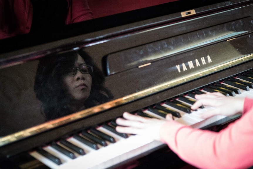 A reflection of pianist Yani Lam's face as she performs.