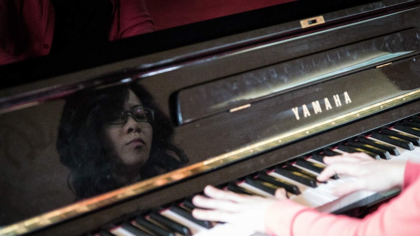 A reflection of pianist Yani Lam's face as she performs.