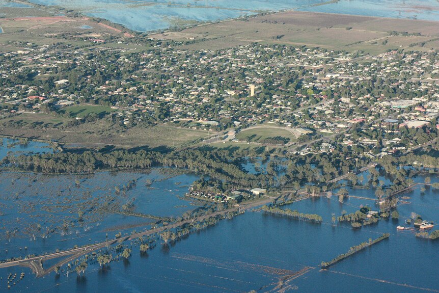 An aerial view of a flooded river, next to a town.