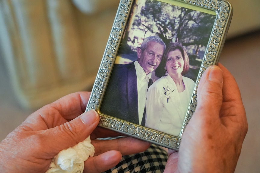 A woman holds a photo of a man and woman.