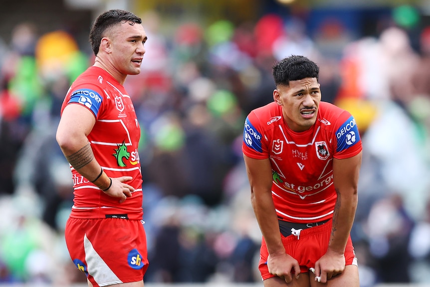 Two St George Illawarra NRL players stand with their hands on their hips after a match.