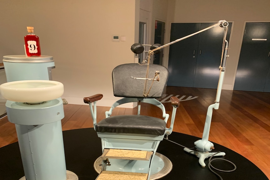 An old dentist char set up with old looking dentist equipment