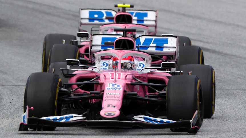 Two, pink Racing Point Formula 1 cars drive one after another