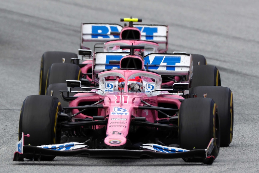 Two, pink Racing Point Formula 1 cars drive one after another